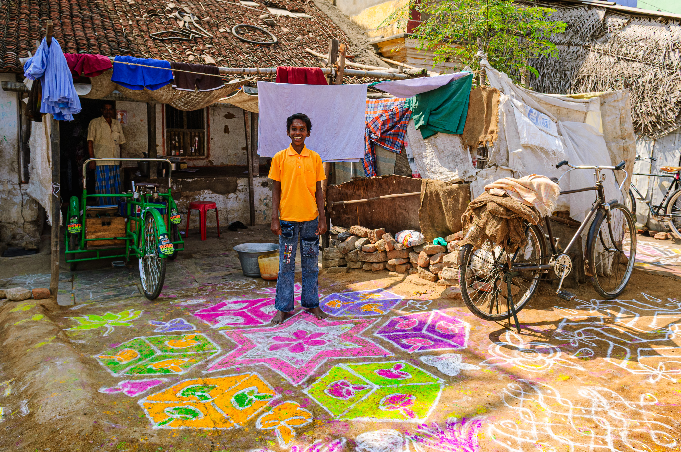 Kanchipuram. Un jeune garçon présente fièrement ses rangoli colorés, tracés à la craie sur le sol terreux au bord de la route.