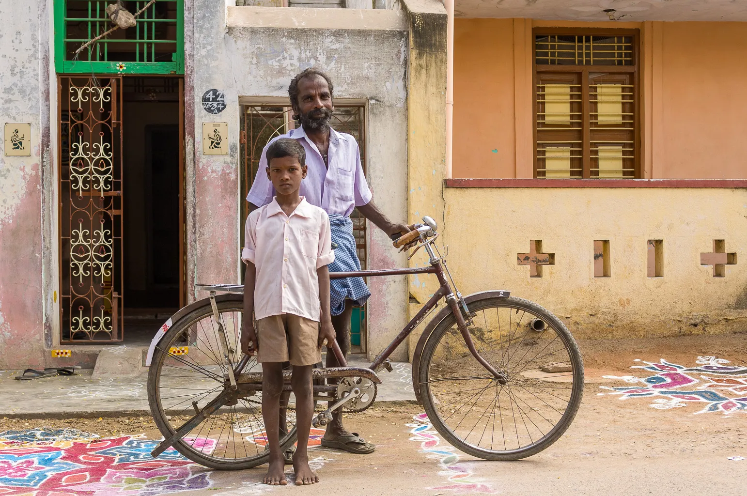 Un père et son fils posent devant leur maison, près d'un vieux vélo, dans une ruelle de Kanchipuram, en Inde.