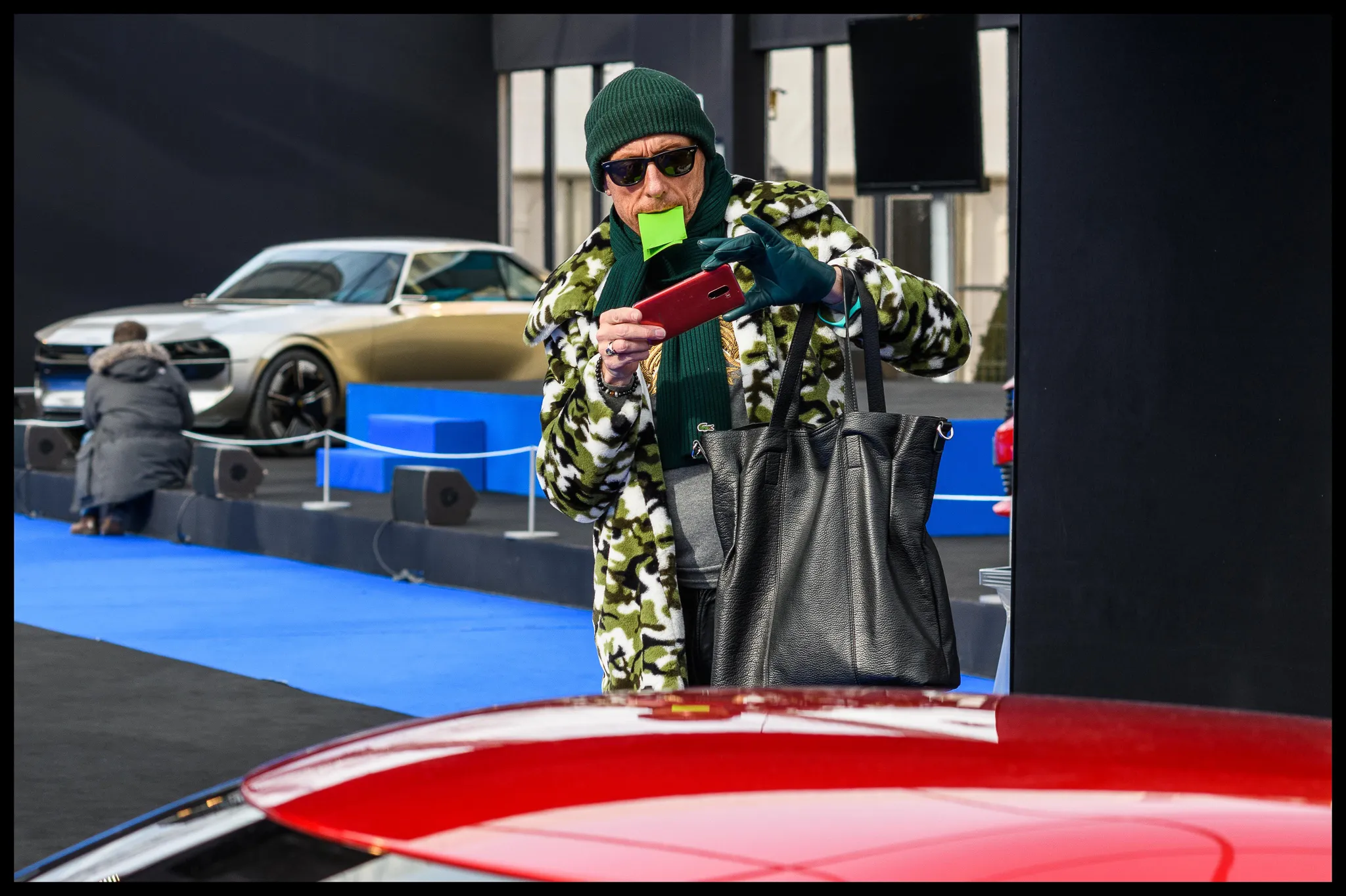 Homme observant un stand automobile avec un post-it à la bouche