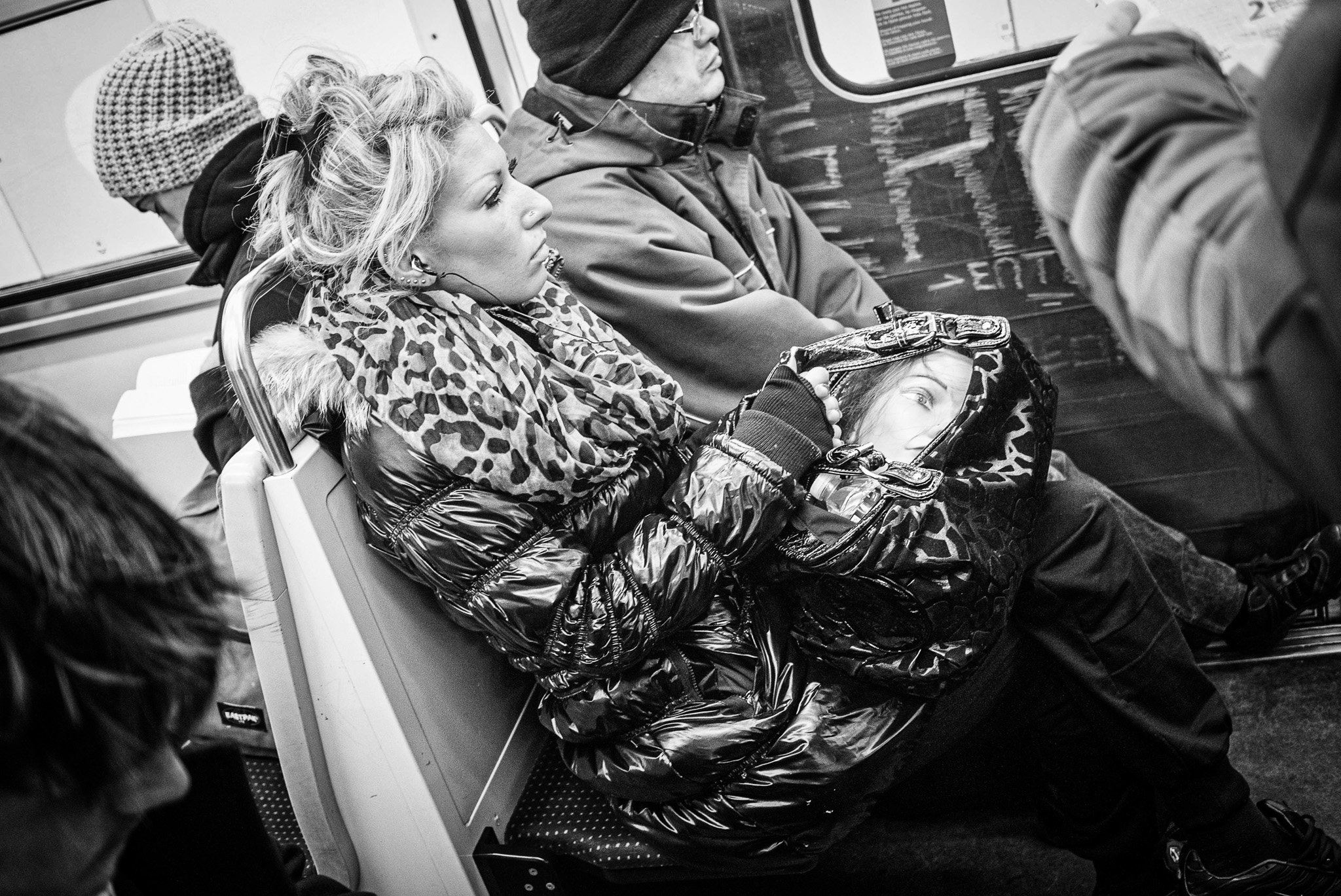 Femme assise dans le métro tenant une tête de mannequin dans son sac, comme un double muet prêt à servir