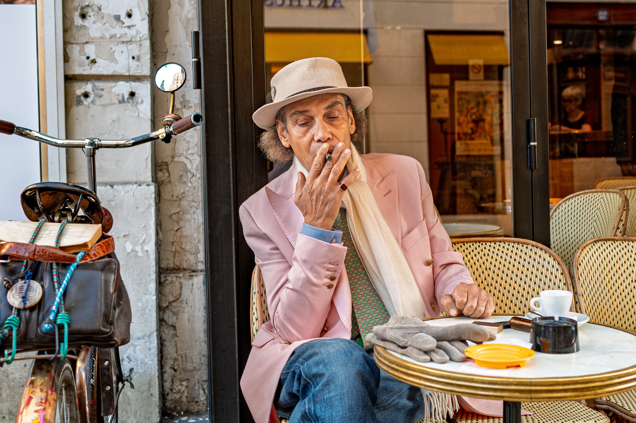 Une homme distingué fume un cigarillo à la terrasse 'un café parisien'