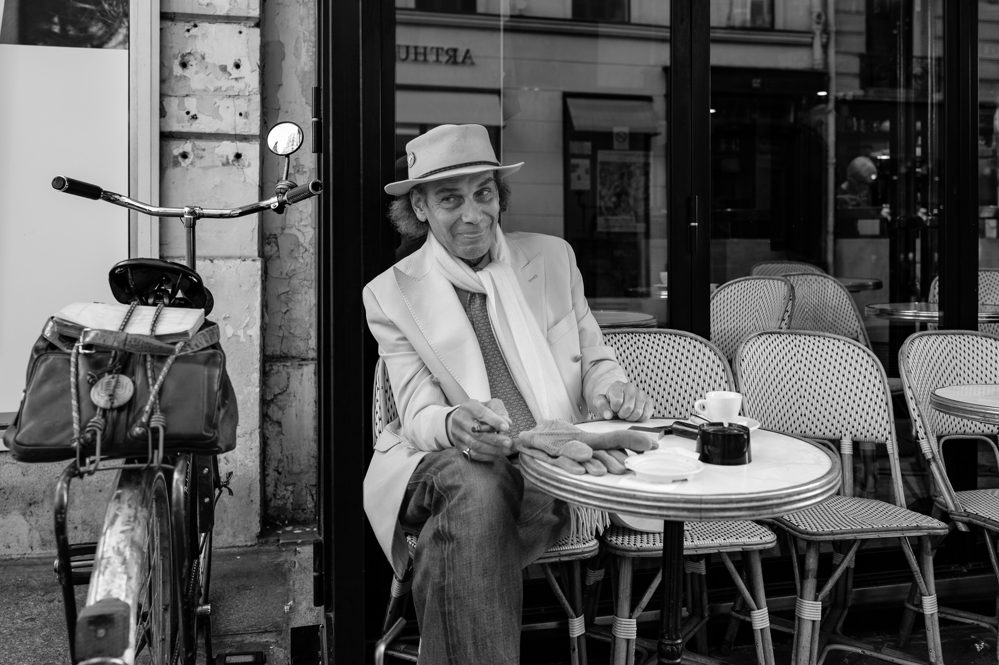 Une homme distingué fume un cigarillo à la terrasse 'un café parisien'