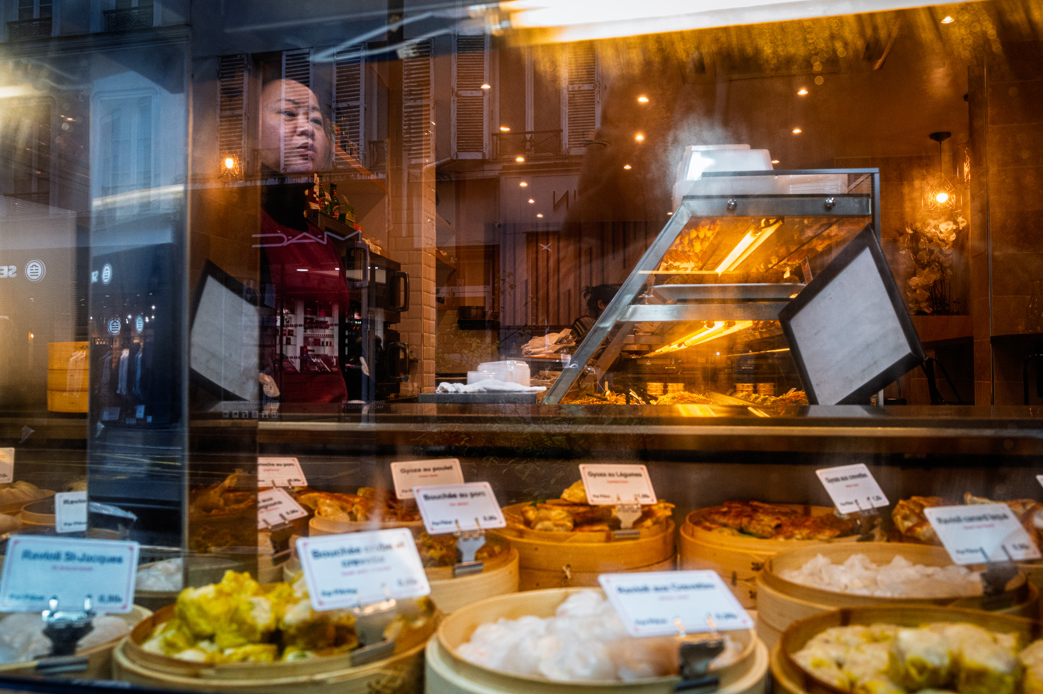 Une femme semble rêver derrière une vitrine embuée.