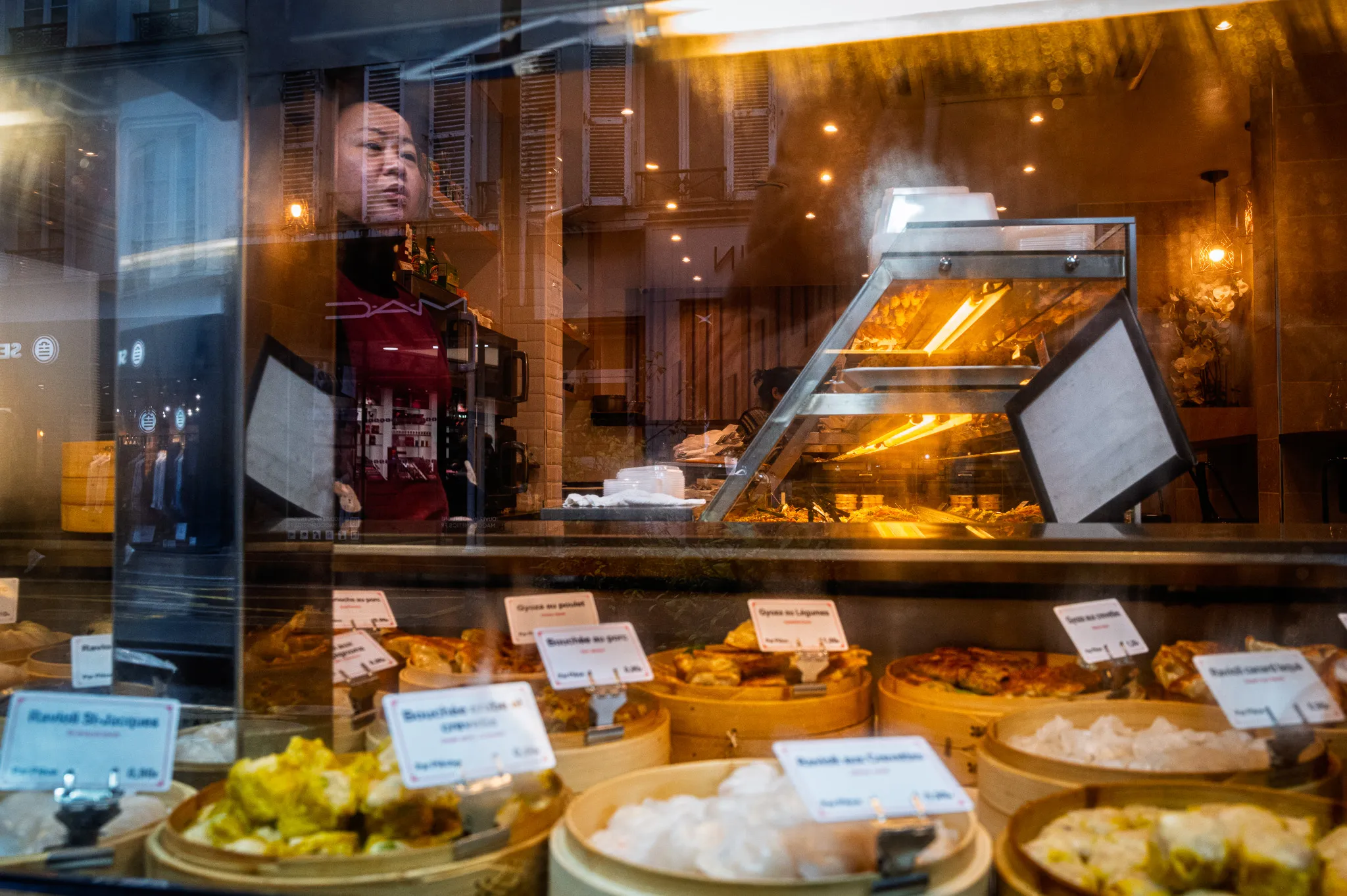 Une femme semble rêver derrière une vitrine embuée.