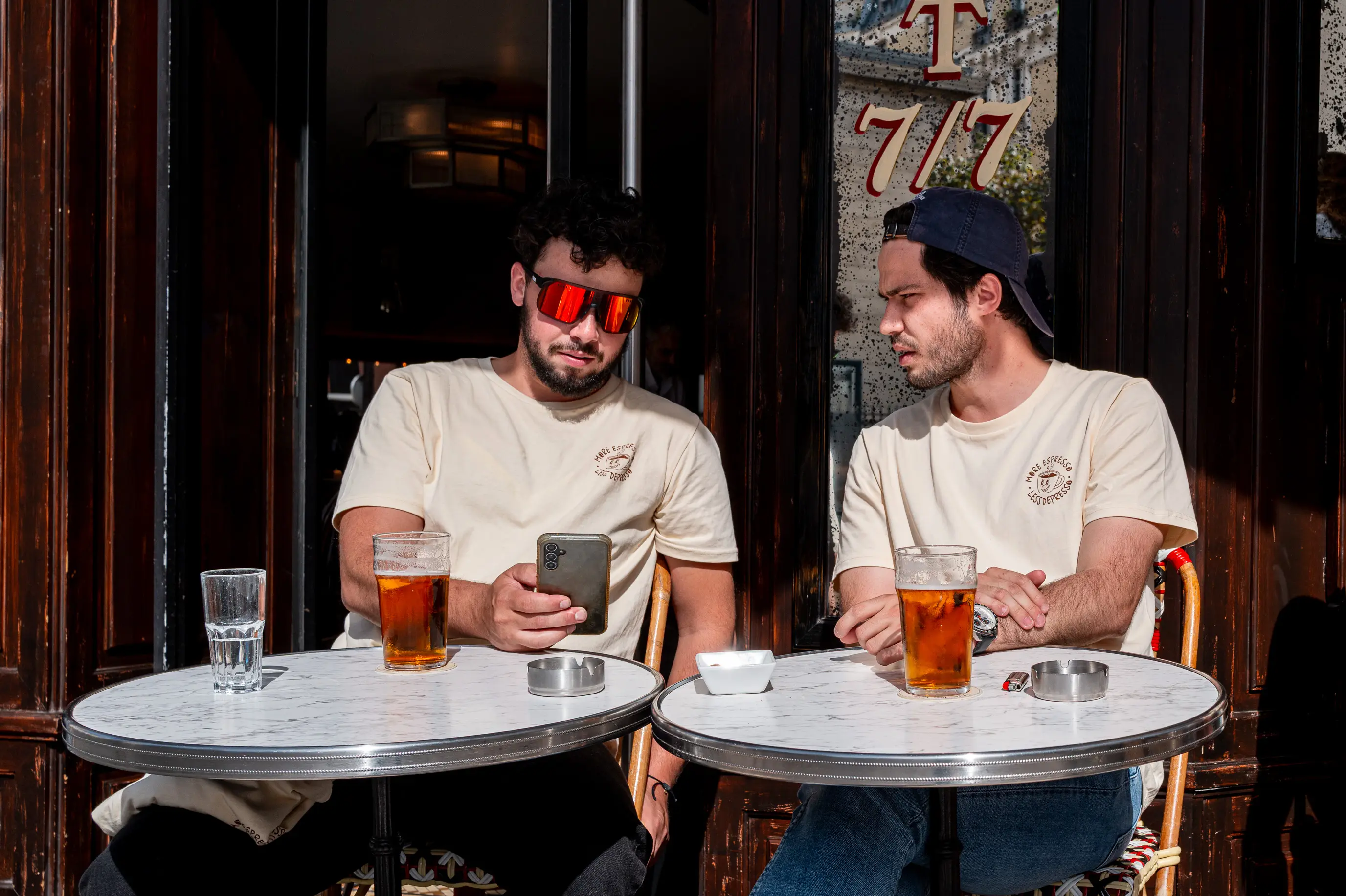 Deux hommes à la terrasse d’un café, l’un regardant son téléphone tandis que l’autre cherche à attirer son attention