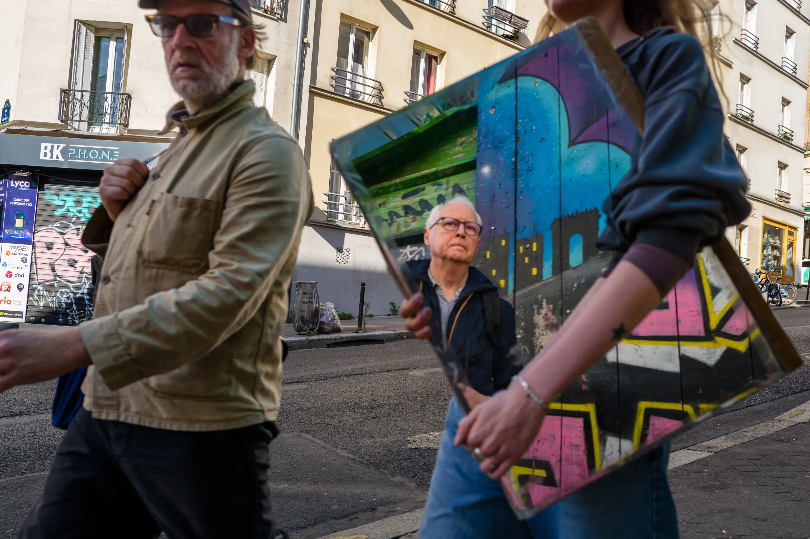 Une femme transporte un miroir dans la rue, où se reflètent des graffitis et le photographe lui-même