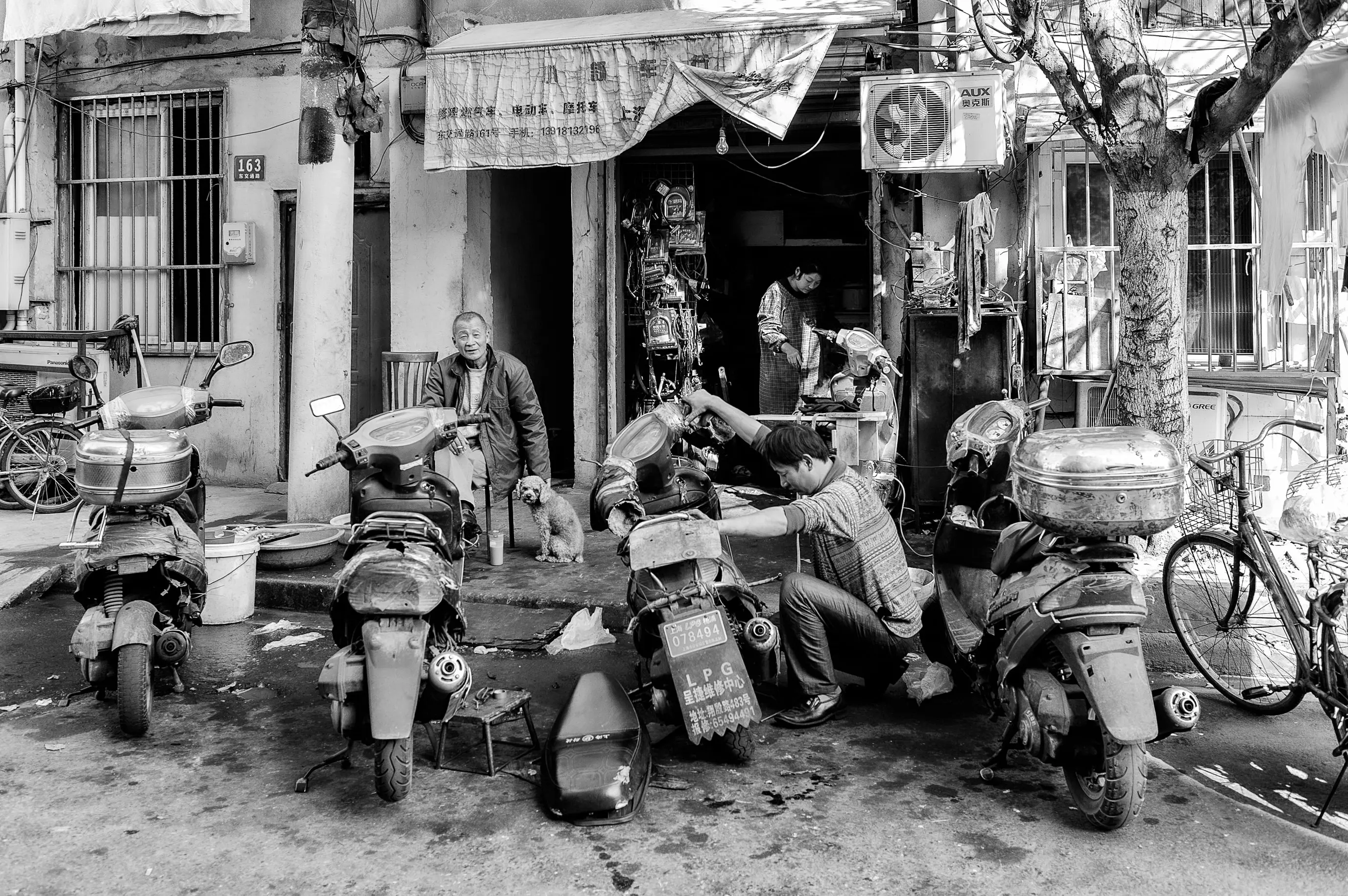 Cette image ne montre pas seulement un réparateur de scooters. Elle montre un espace où le travail,