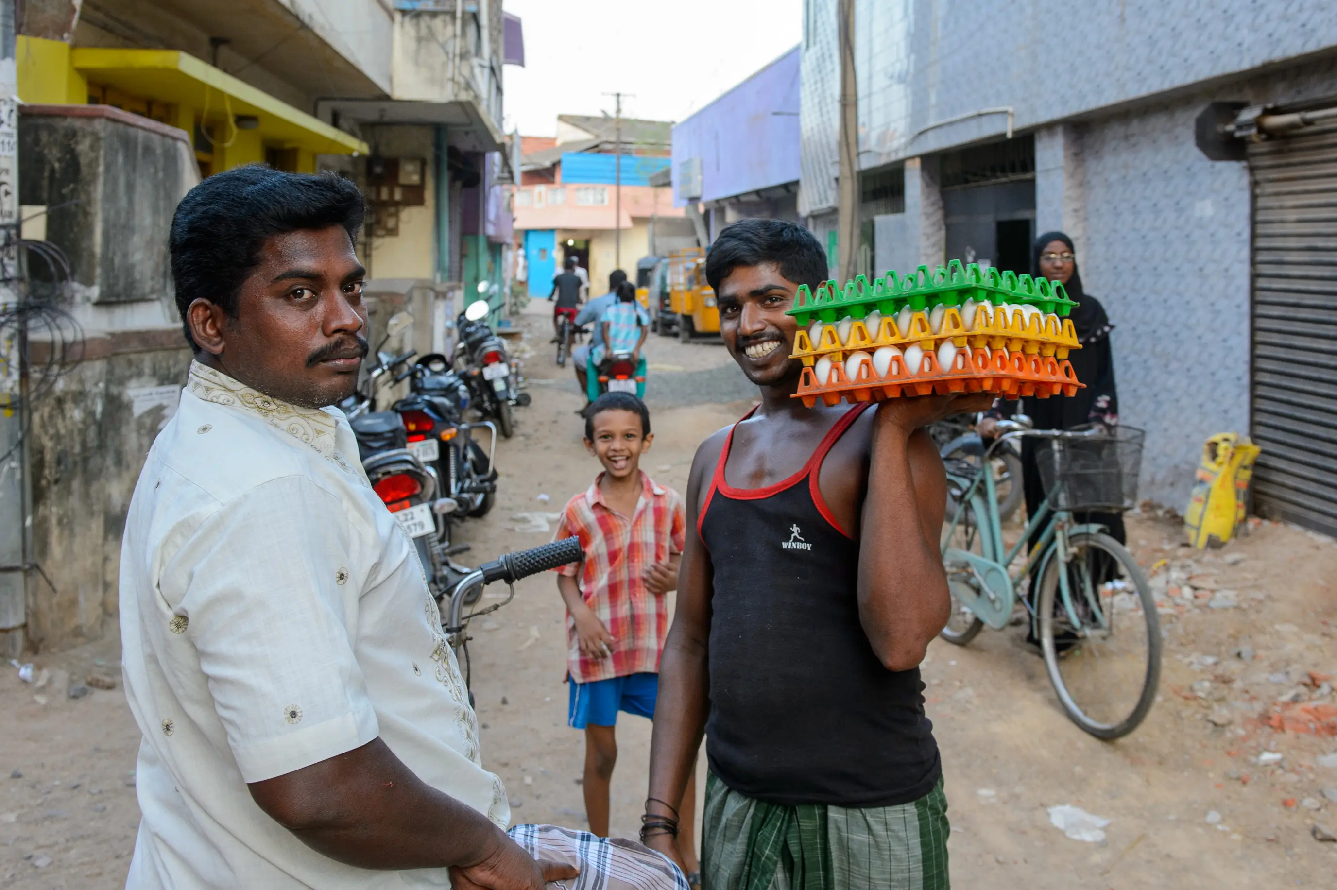 Porteur d'œufs entouré d'un homme et d'un enfant dans une rue en Inde
