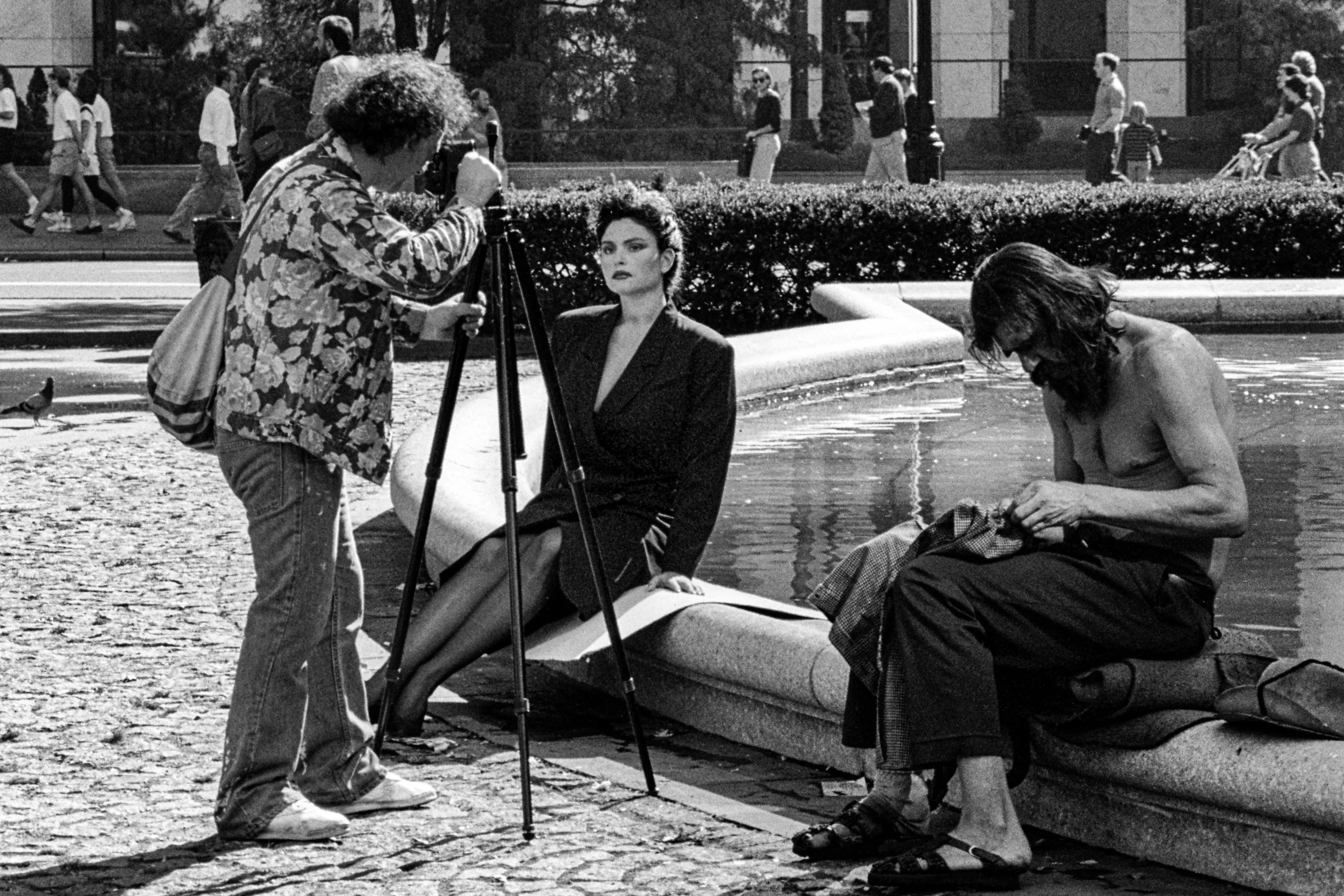Séance photo devant le Plaza à New York, avec un mannequin, un photographe et un homme assis au bord d'une fontaine.
