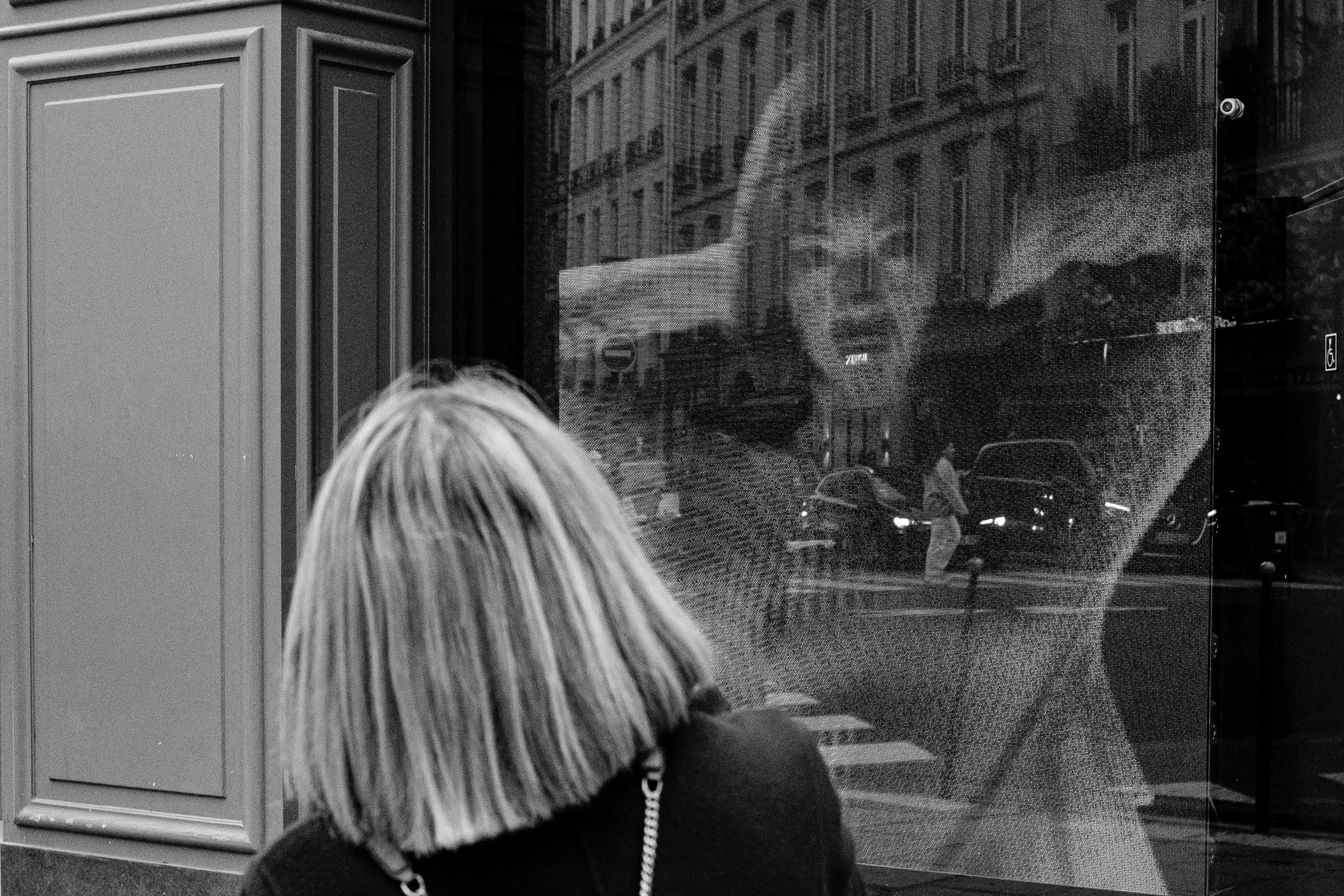 Une femme devant une vitrine où une image publicitaire semble devenir son reflet