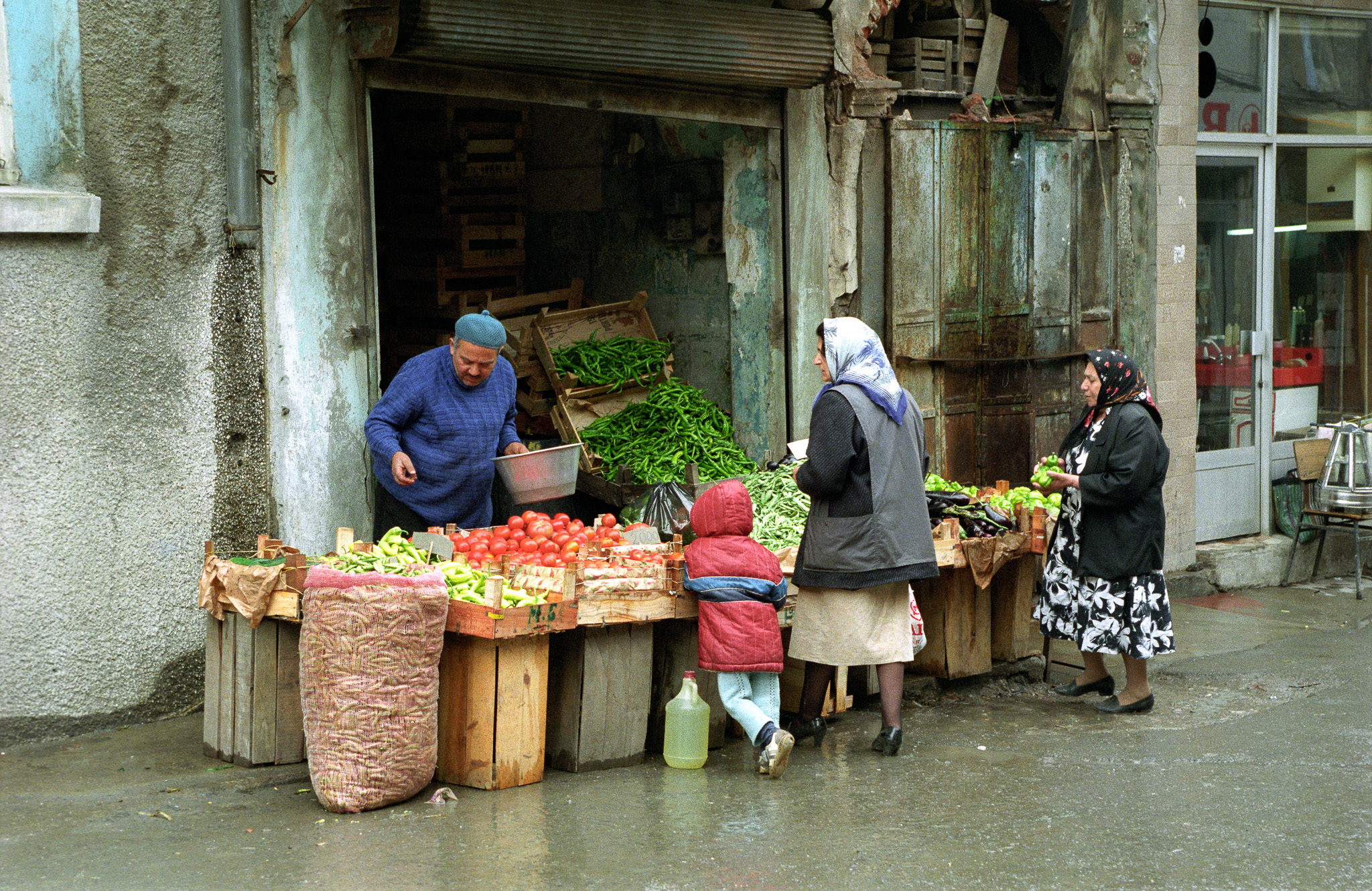 Un vendeur propose tomates, poivrons et haricots sur un étal improvisé devant une échoppe délabrée à Istanbul, années 1990