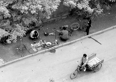 Des réparateurs de bicyclettes travaillent à même le trottoir. Les crevaisons sont fréquentes.