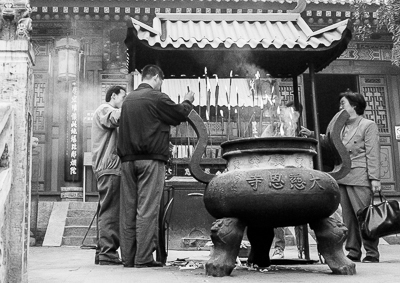 Des visiteurs déposent leurs bâtonnets d’encens dans un grand brûle-parfum du temple.