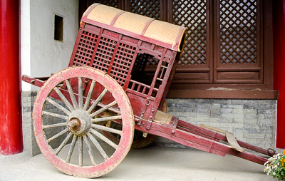 Une ancienne voiture à bras attend sous les galeries du temple.