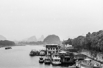 Plusieurs bateaux amarrés sur la rivière à Guilin, devant les reliefs karstiques.