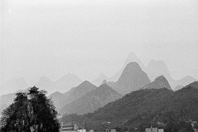 Un pavillon perché sur un piton rocheux, devant les reliefs karstiques de Guilin qui s’effacent dans la brume.
