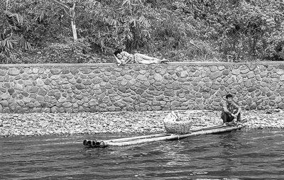 Un homme se repose sur un mur de pierre tandis qu’un batelier passe sur la rivière.