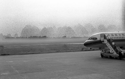 Un avion attend sur le tarmac au petit matin, dans une brume épaisse, avant le départ pour Canton.