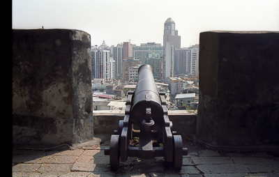 Un canon de la forteresse du Mont pointe vers la ville moderne de Macao.