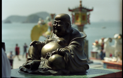 Une statuette de Bouddha rieur veille sur les embarcations du port.