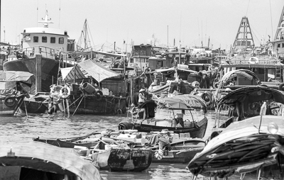 Embarcations de travail et habitations flottantes composent un paysage portuaire très dense.