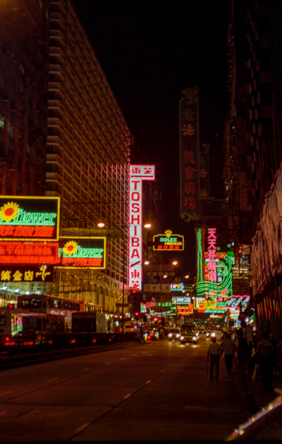 Enseignes au néon et circulation nocturne dans les rues de Kowloon.