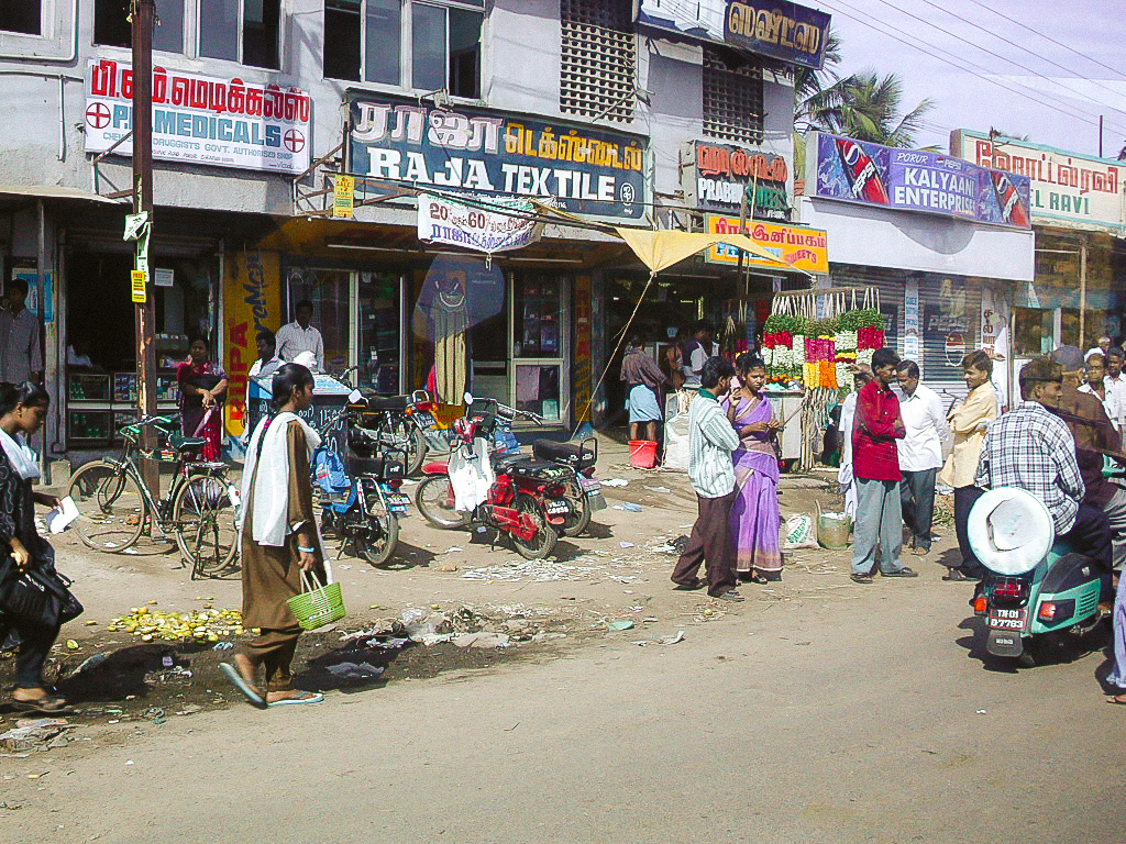 Commerces, vélos, motos et piétons au bord de la route.