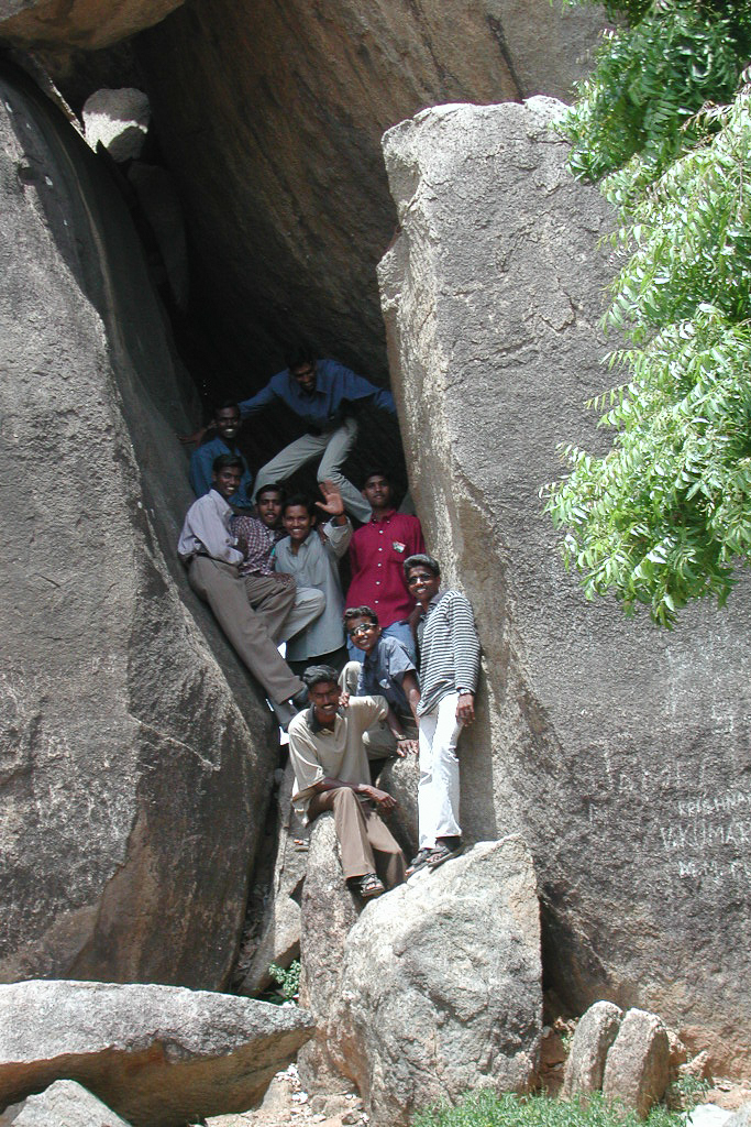 Des visiteurs se faufilent dans un passage entre deux rochers.