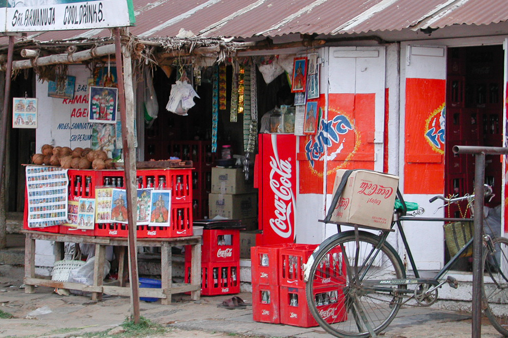Une petite épicerie, ses casiers de boissons et une bicyclette.