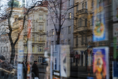 Reflets de façades et de passants dans une vitre à Prague