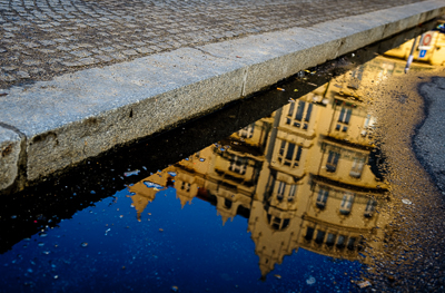 Reflet d’une façade dans une flaque sur les pavés de Prague