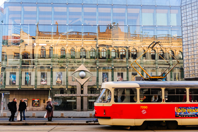 Tramway rouge et crème devant une façade vitrée qui reflète la ville