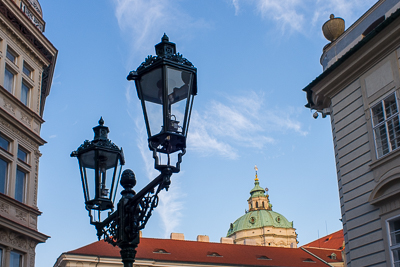 Lampadaires anciens devant les toits et la coupole de Prague