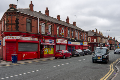 Alignement de commerces aux façades rouges dans une rue d’Anfield