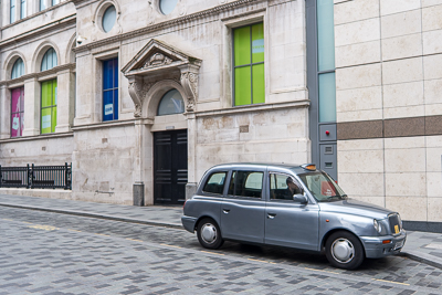 Taxi londonien stationné devant une façade aux fenêtres colorées à Liverpool