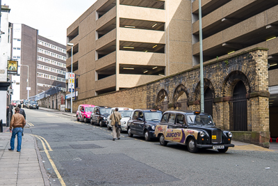 Rue de Liverpool bordée d’un parking et d’anciens murs de briques