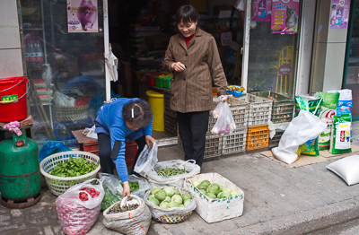 Marchande de légumes devant son commerce à Shanghai