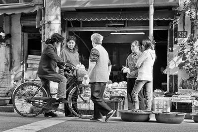 Conversation devant les étals d'un marché de quartier à Shanghai
