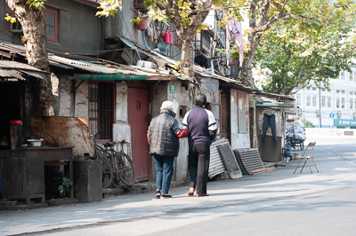 Habitants marchant devant des maisons basses d'un ancien quartier de Shanghai