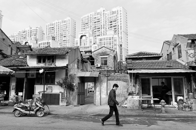 Habitant marchant devant des maisons basses promises à la transformation à Shanghai