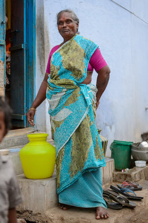 Une femme en sari près des bidons d'eau