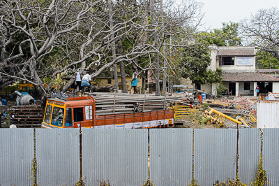 Un camion orange apparaît derrière la palissade d'un chantier.