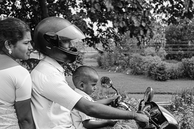 Une famille de trois personnes circule à moto le long de la route.