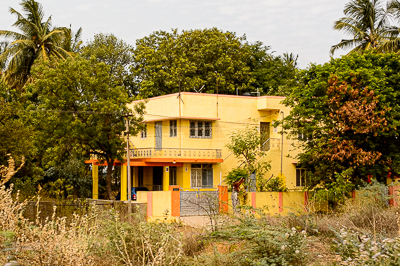 Une maison jaune et rouge se cache parmi les arbres.
