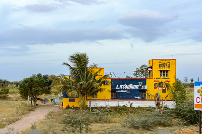 Une façade peinte aux couleurs de Dalmia Vijayam Cement se détache dans un paysage de palmiers.
