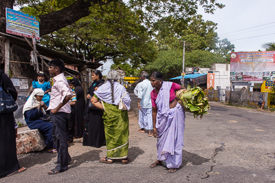 Saris, sacs et conversations composent une scène animée au bord de la chaussée.