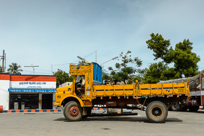 Un camion jaune traverse une station-service sous le grand ciel bleu du Tamil Nadu.