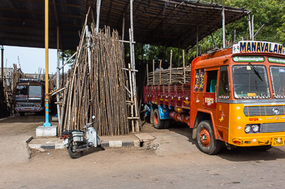 Un camion orange attend sous un hangar, à côté d'une nouvelle réserve de bambous.
