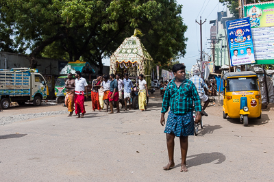 Le petit sanctuaire processionnel avance entre un rickshaw et une camionnette sans arrêter la circulation.