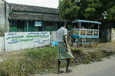 Un homme passe devant une charrette vitrée chargée de snacks, au bord d'une route du Tamil Nadu.